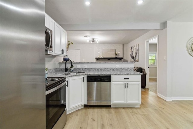 kitchen with stainless steel appliances, a sink, white cabinetry, and light stone countertops