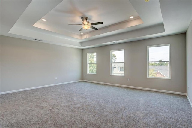 carpeted spare room with ceiling fan and a tray ceiling