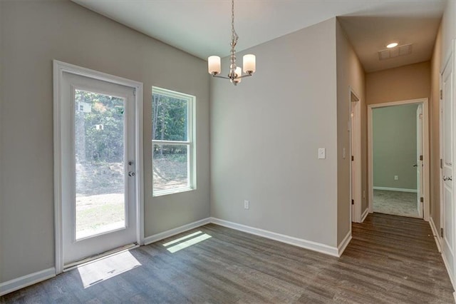 unfurnished dining area with dark hardwood / wood-style flooring and an inviting chandelier