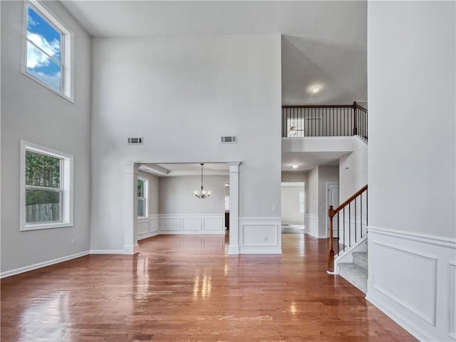 unfurnished living room featuring a high ceiling, a notable chandelier, and hardwood / wood-style flooring