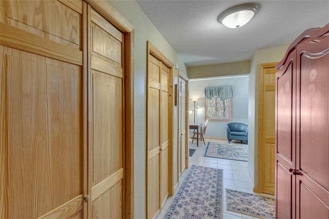 hall featuring light tile patterned floors and a textured ceiling