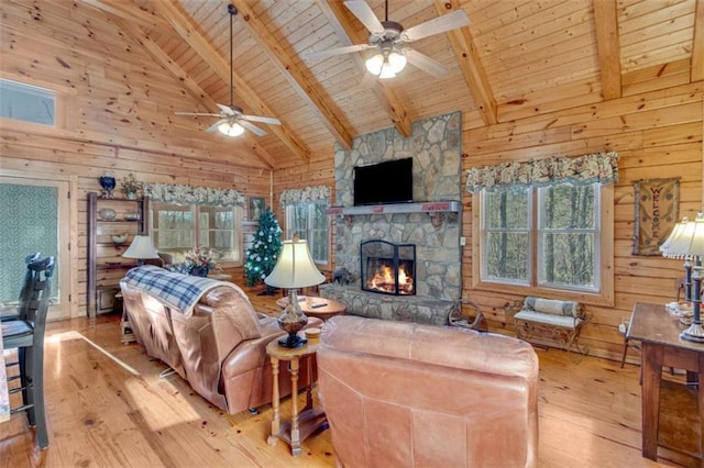 living room featuring beam ceiling, a stone fireplace, light hardwood / wood-style floors, and high vaulted ceiling