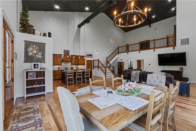 dining space with a towering ceiling, a chandelier, and light hardwood / wood-style floors