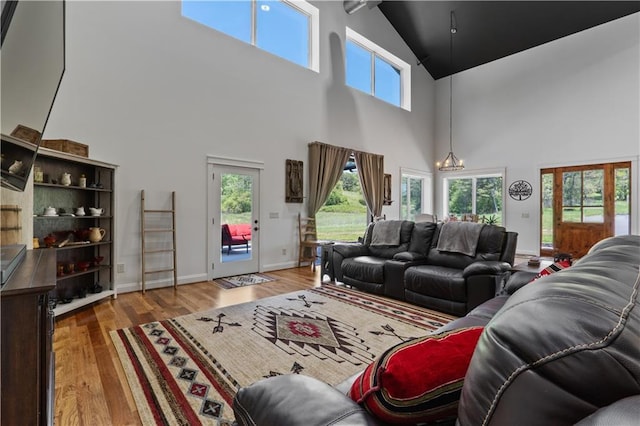 living room featuring light hardwood / wood-style flooring, a chandelier, and a high ceiling