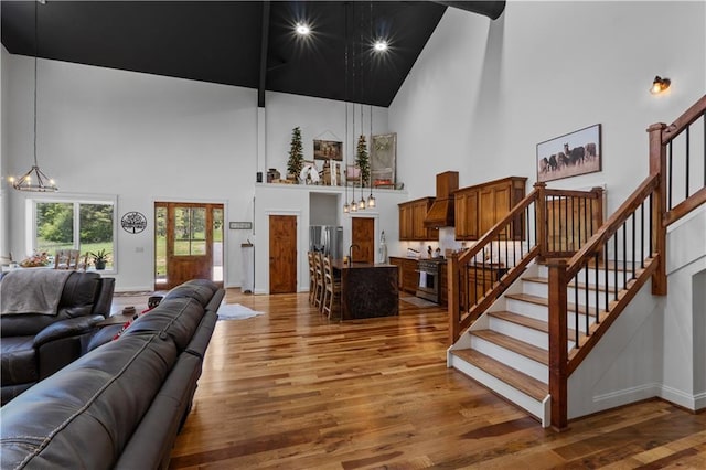 living room with a chandelier, a towering ceiling, hardwood / wood-style flooring, and sink