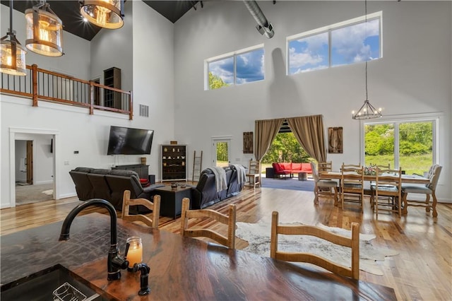 living room with wood-type flooring, a high ceiling, an inviting chandelier, and sink