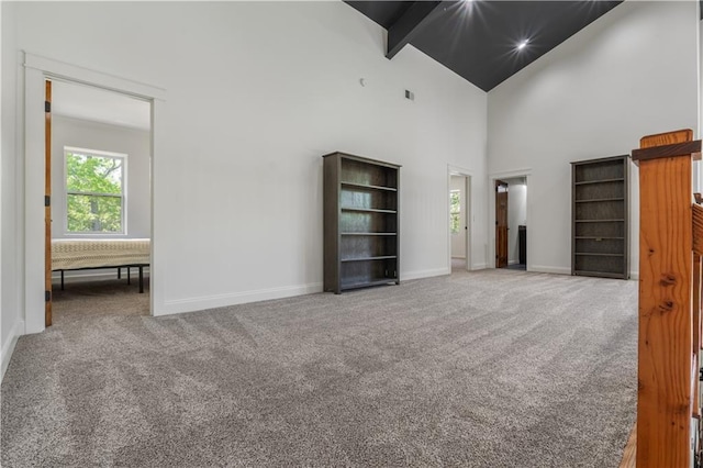 unfurnished bedroom featuring carpet, beamed ceiling, and high vaulted ceiling