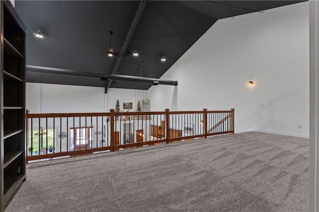 carpeted spare room featuring high vaulted ceiling