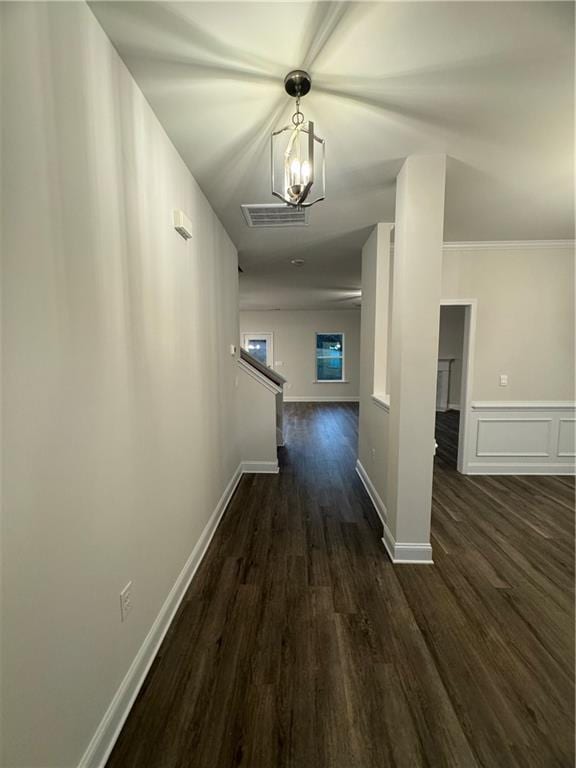 hall featuring crown molding, dark hardwood / wood-style floors, and a notable chandelier