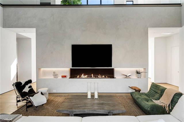 living room featuring a lit fireplace and wood finished floors