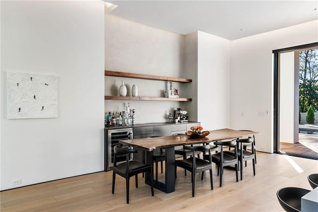 dining space featuring a bar, light wood-style flooring, and wine cooler