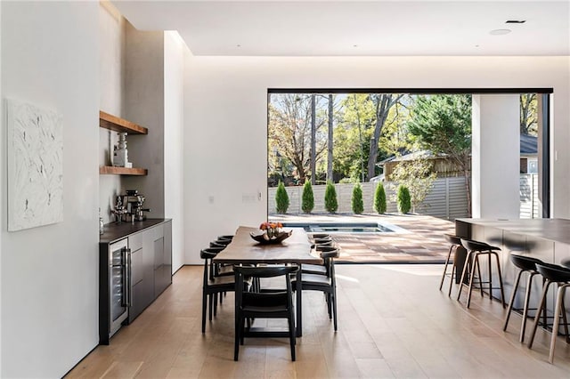 dining room featuring a wealth of natural light, light wood-style flooring, and wine cooler