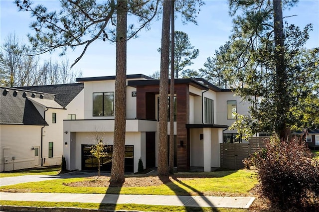 back of property featuring a garage, driveway, fence, and stucco siding