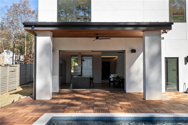 property entrance featuring ceiling fan, fence, and stucco siding