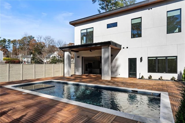 rear view of house featuring stucco siding, fence, a fenced in pool, and a patio