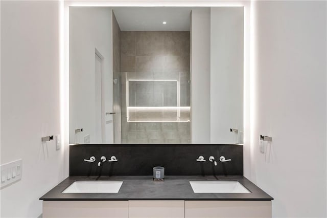 full bath featuring double vanity, backsplash, a sink, and tiled shower