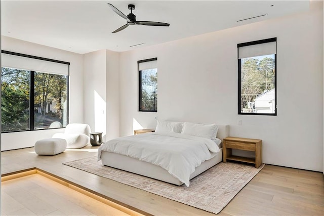 bedroom with a ceiling fan, multiple windows, and wood finished floors