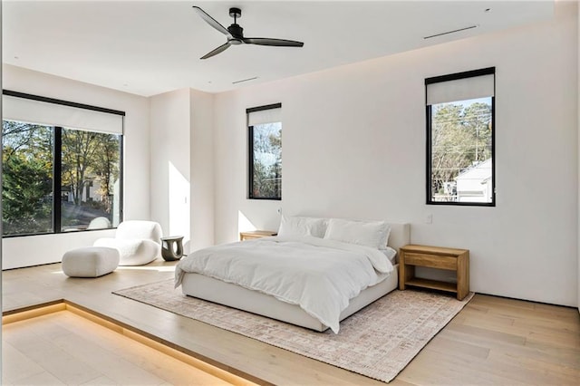 bedroom with ceiling fan, multiple windows, and wood finished floors