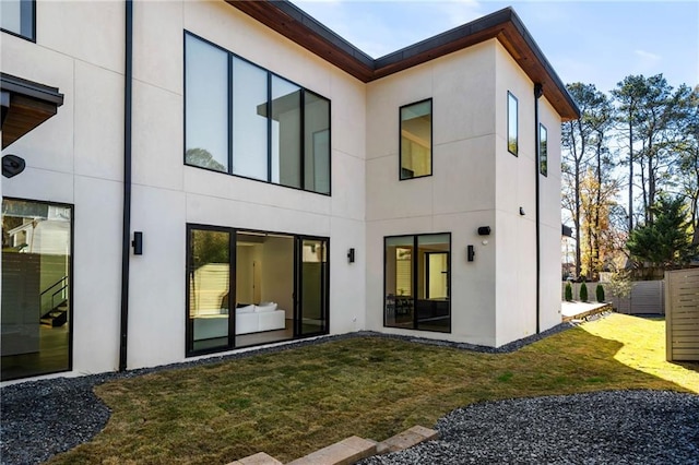 rear view of property with a lawn and stucco siding