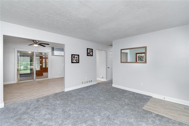 carpeted empty room with a ceiling fan, visible vents, a textured ceiling, and baseboards