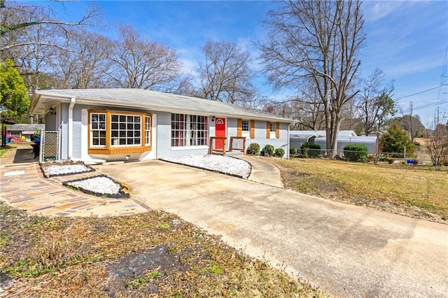 ranch-style house featuring concrete driveway, a front lawn, and fence