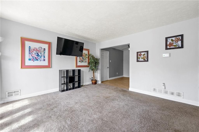 unfurnished living room featuring baseboards, visible vents, carpet floors, and a textured ceiling