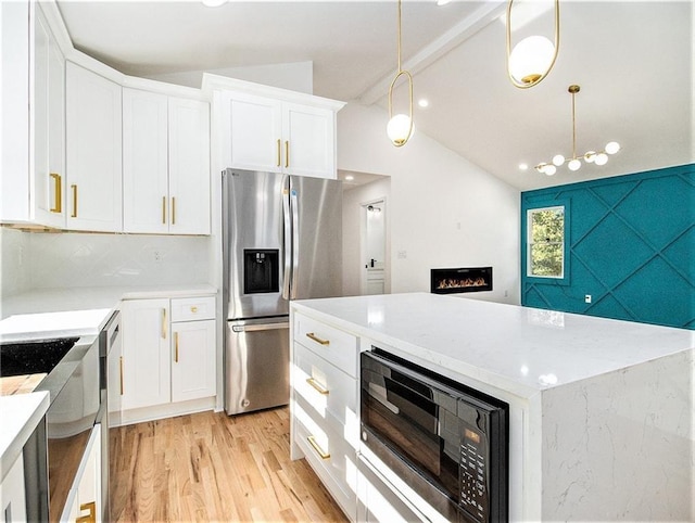 kitchen with light wood finished floors, lofted ceiling with beams, white cabinets, black microwave, and stainless steel fridge