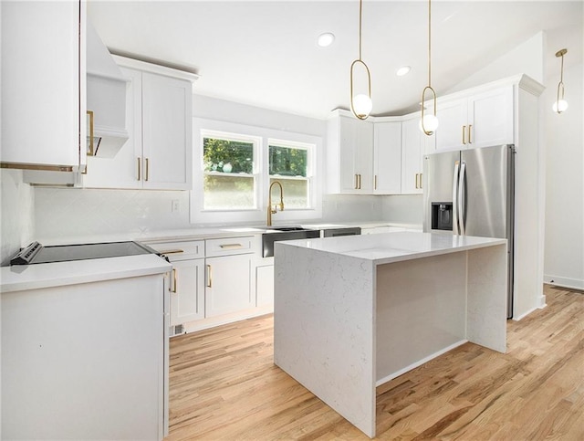 kitchen with white cabinetry, tasteful backsplash, a center island, and light wood finished floors