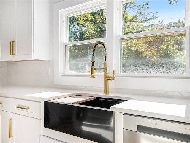 kitchen featuring dishwasher, backsplash, white cabinetry, and a sink