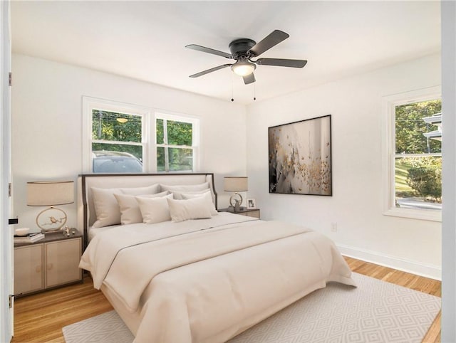 bedroom with light wood-style floors, baseboards, and ceiling fan