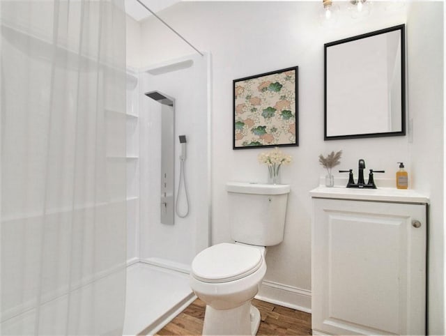 bathroom with toilet, vanity, walk in shower, and wood finished floors