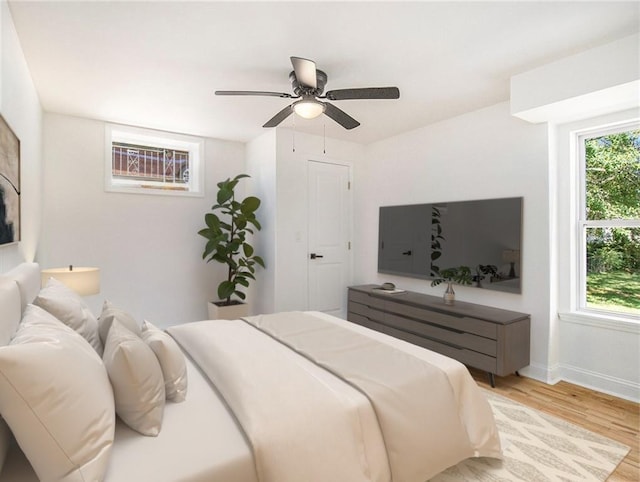 bedroom with light wood finished floors, baseboards, and a ceiling fan