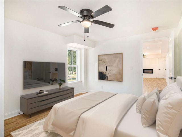 bedroom featuring a ceiling fan, baseboards, and light wood finished floors