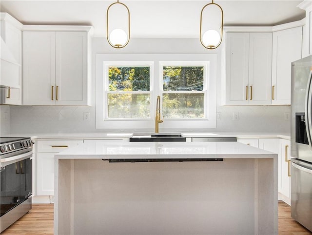 kitchen with a kitchen island, light wood-style flooring, white cabinets, stainless steel appliances, and a sink