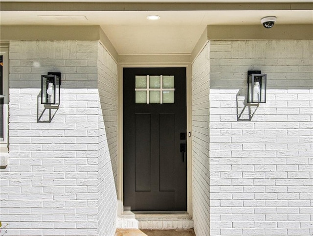 view of exterior entry featuring brick siding