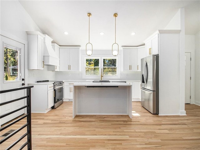 kitchen featuring premium range hood, appliances with stainless steel finishes, a center island, and a healthy amount of sunlight