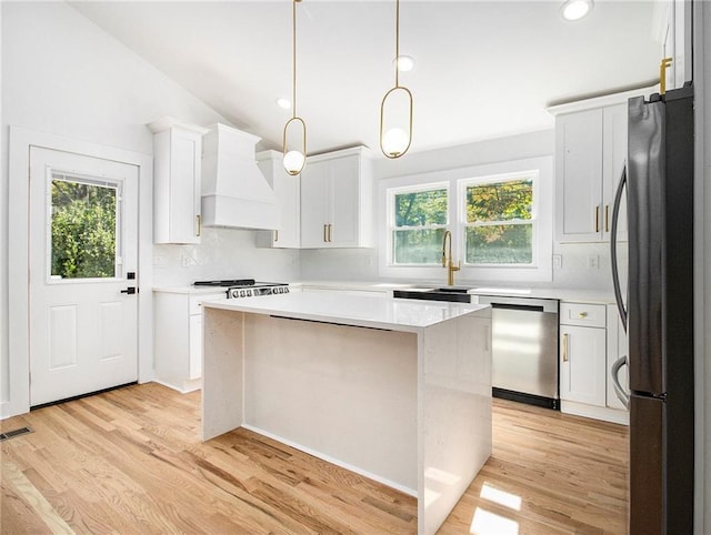 kitchen with a sink, stainless steel appliances, light wood-type flooring, and custom exhaust hood