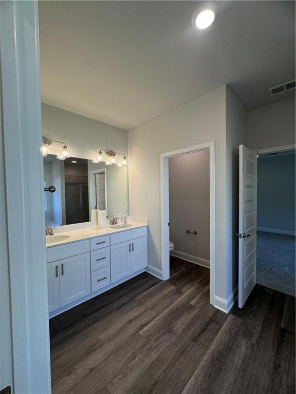 bathroom featuring wood-type flooring, vanity, toilet, and walk in shower