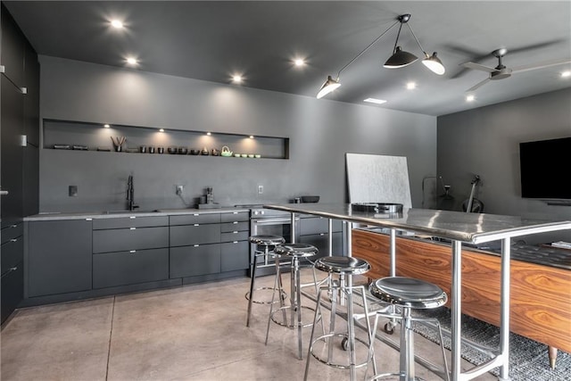 kitchen with sink, a breakfast bar area, gray cabinetry, hanging light fixtures, and ceiling fan