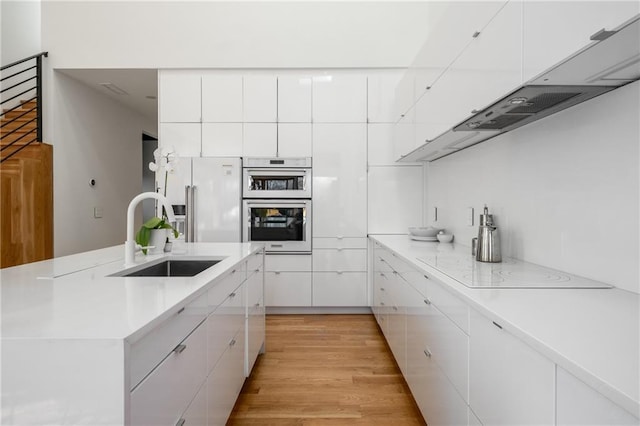 kitchen featuring sink, white cabinets, white appliances, and light wood-type flooring