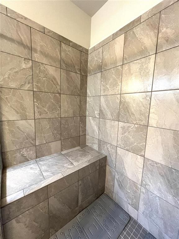 bathroom with tiled shower and tile patterned floors