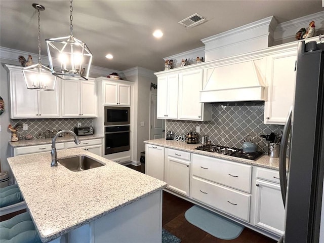 kitchen featuring decorative light fixtures, a kitchen breakfast bar, sink, appliances with stainless steel finishes, and a center island with sink