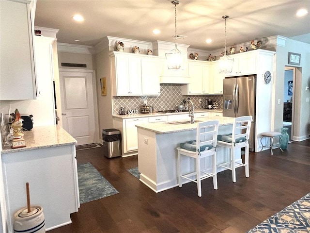 kitchen with dark hardwood / wood-style flooring, light stone countertops, pendant lighting, and a center island with sink