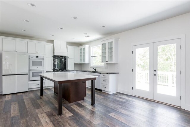 kitchen featuring a breakfast bar area, plenty of natural light, white appliances, and a kitchen island