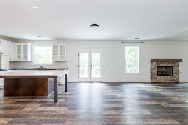 kitchen featuring a breakfast bar, dark hardwood / wood-style flooring, white cabinets, a kitchen island, and a stone fireplace