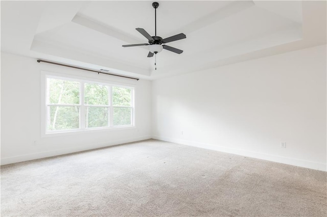 unfurnished room with ceiling fan, carpet floors, and a raised ceiling