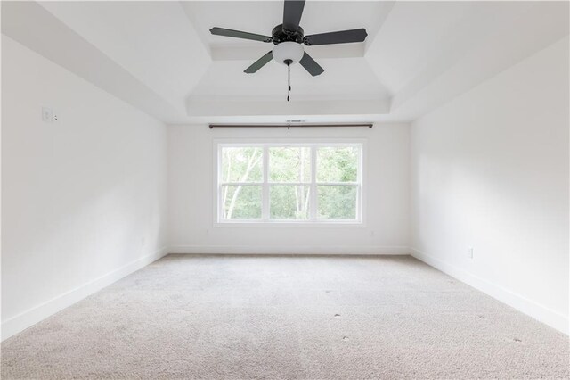 carpeted empty room with ceiling fan and a raised ceiling