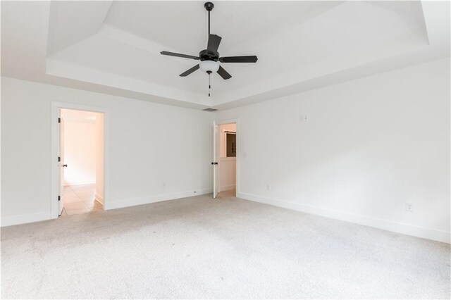 carpeted spare room featuring a tray ceiling and ceiling fan