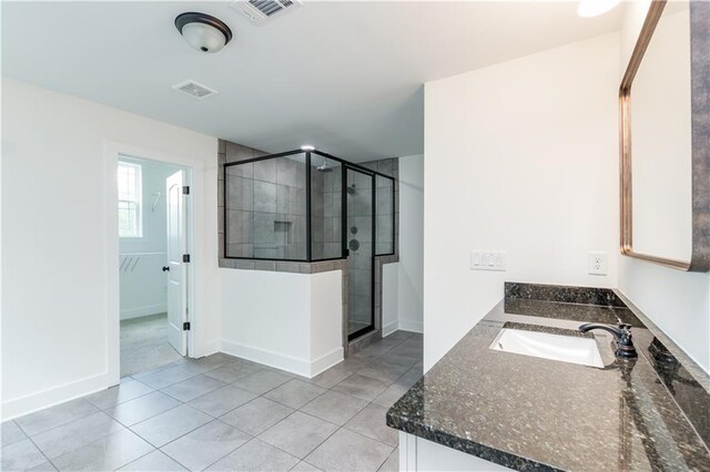 bathroom with walk in shower, vanity, and tile patterned floors