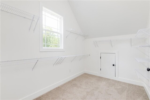 walk in closet with light carpet and vaulted ceiling